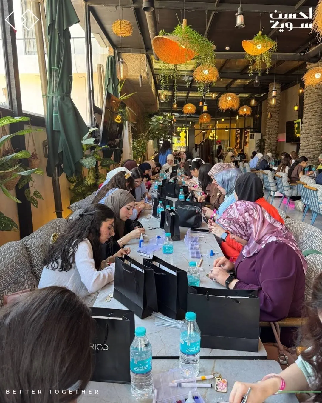 مشاركات حول طاولات طويلة يعملن على قطعهن
