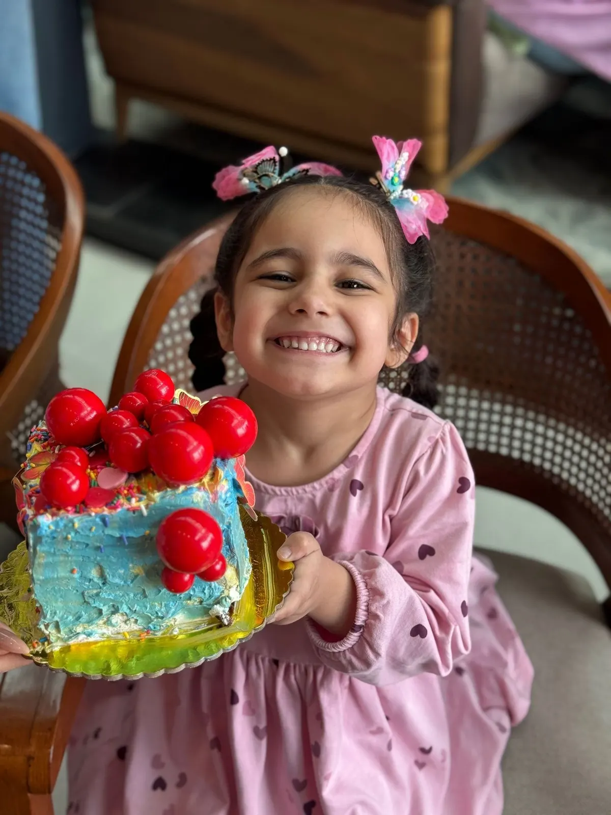 طفلة مبتسمة تحمل كعكة زيّنتها بالكرز