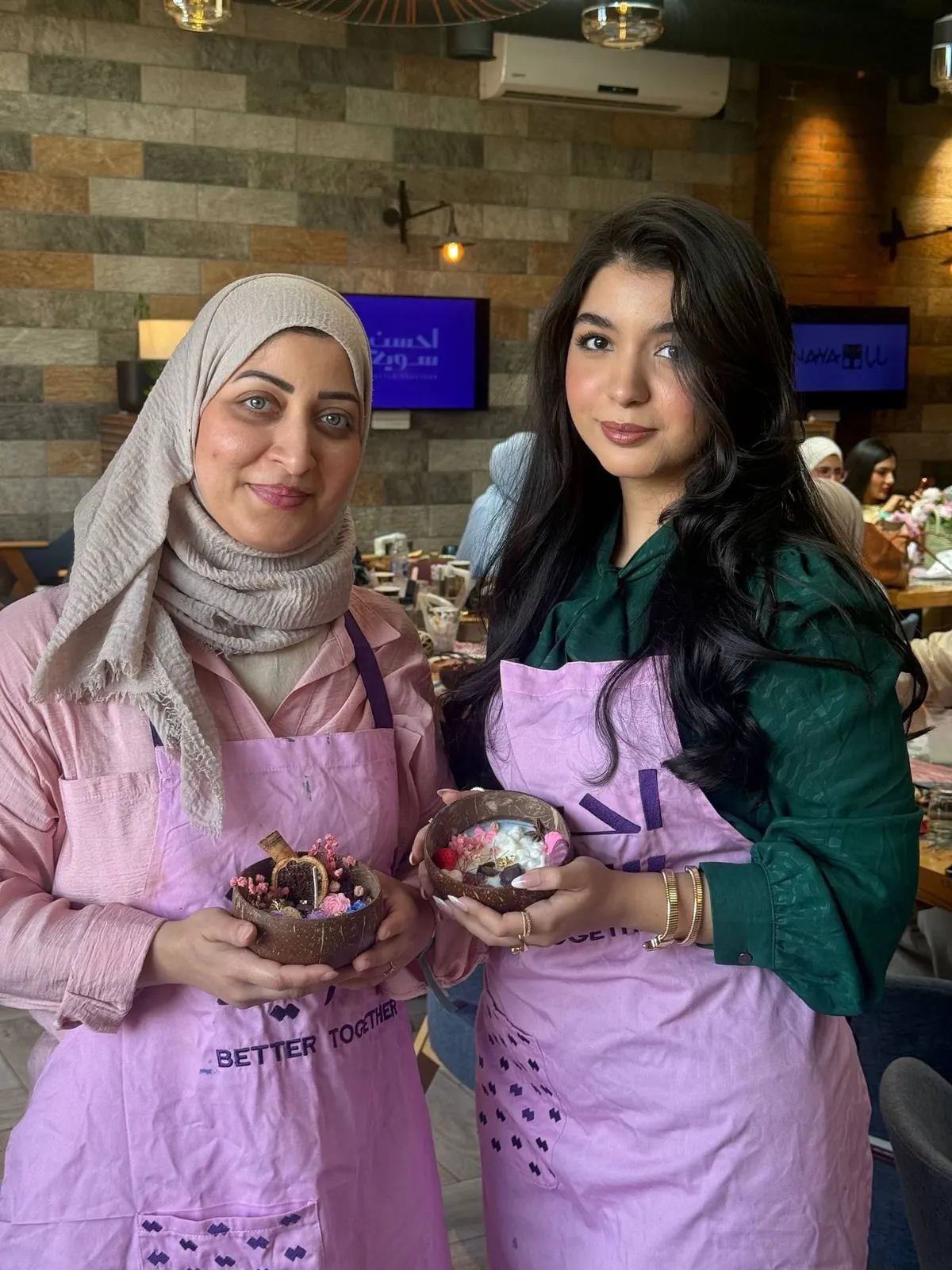 مشاركتان بمريلتين ورديتين تحملان الشموع التي صنعتاها