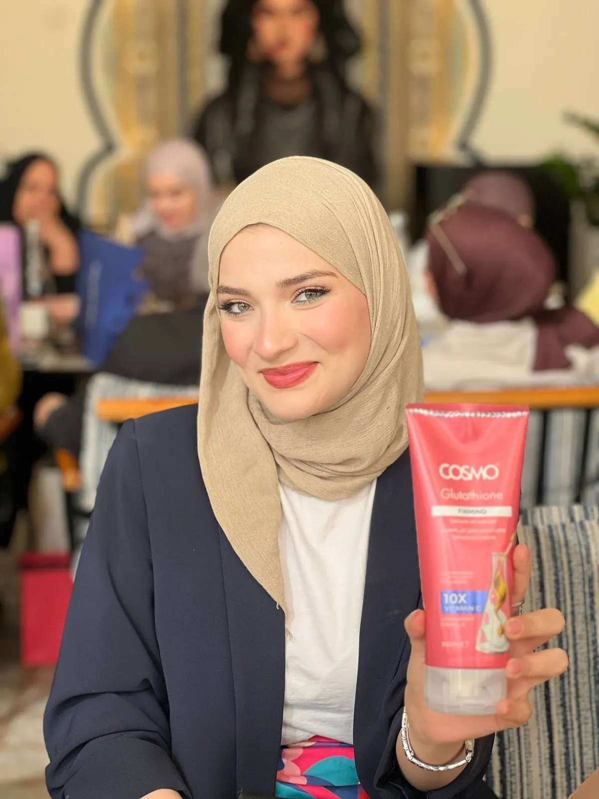 مشاركة مبتسمة تحمل منتجاً من Cosmo