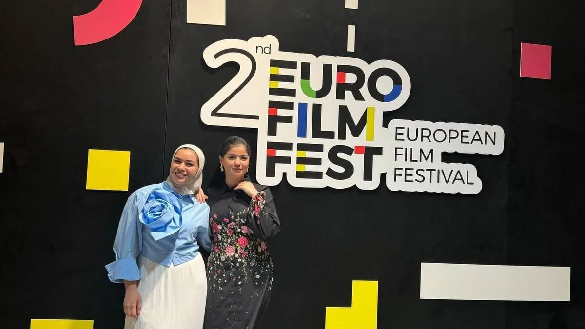 Two participants in front of the 2nd European Film Festival backdrop