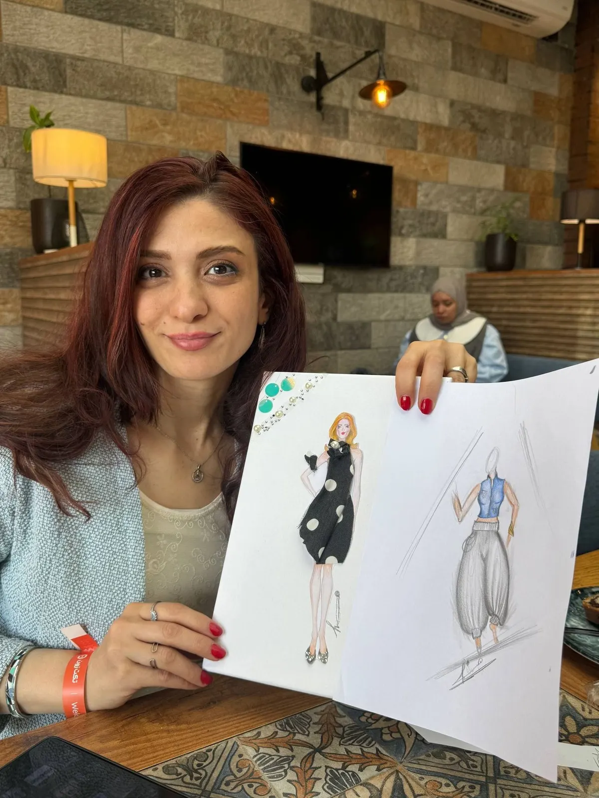 مشاركة تعرض رسمة تصميم الأزياء التي لوّنتها