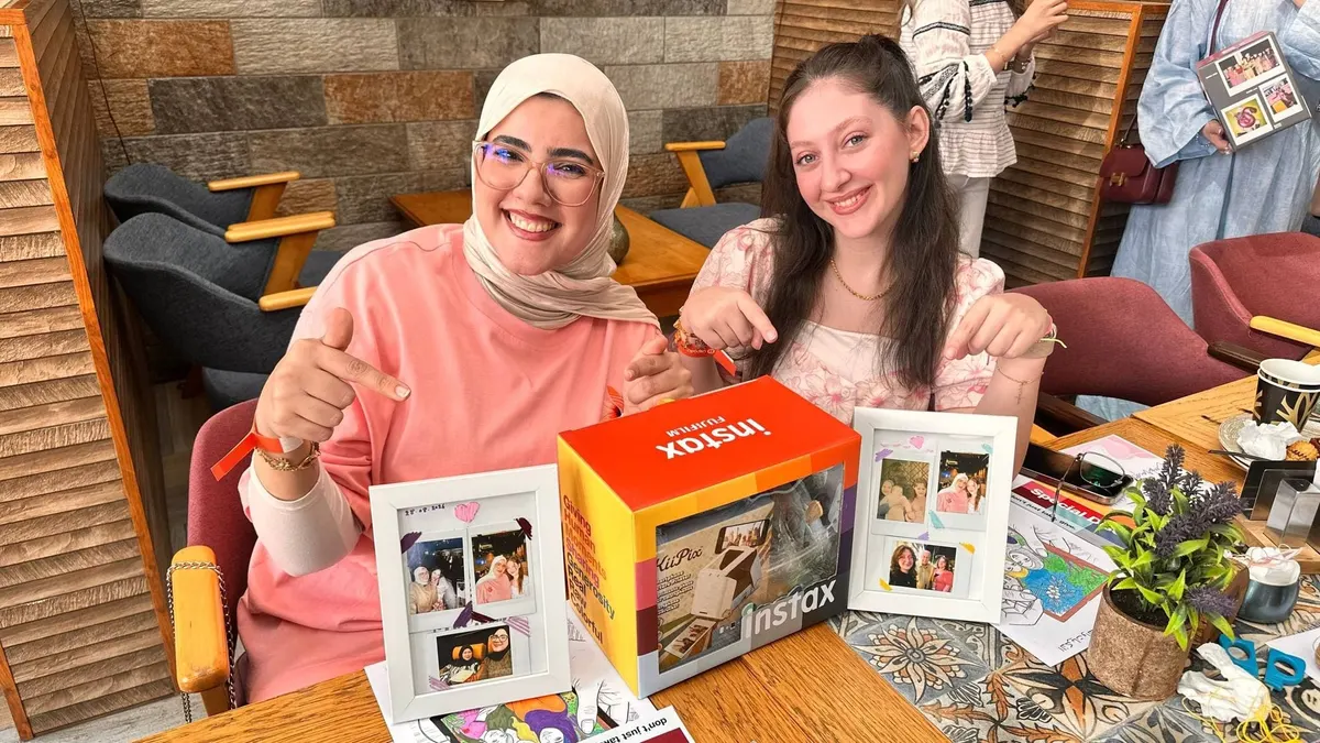 مشاركتان مبتسمتان تعرضان صوراً فورية داخل إطارات