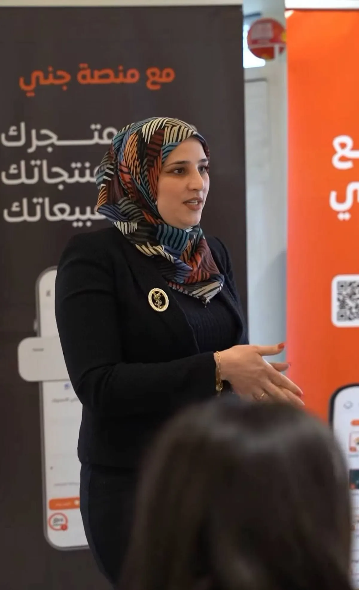 متحدثة أمام لافتة منصة جني
