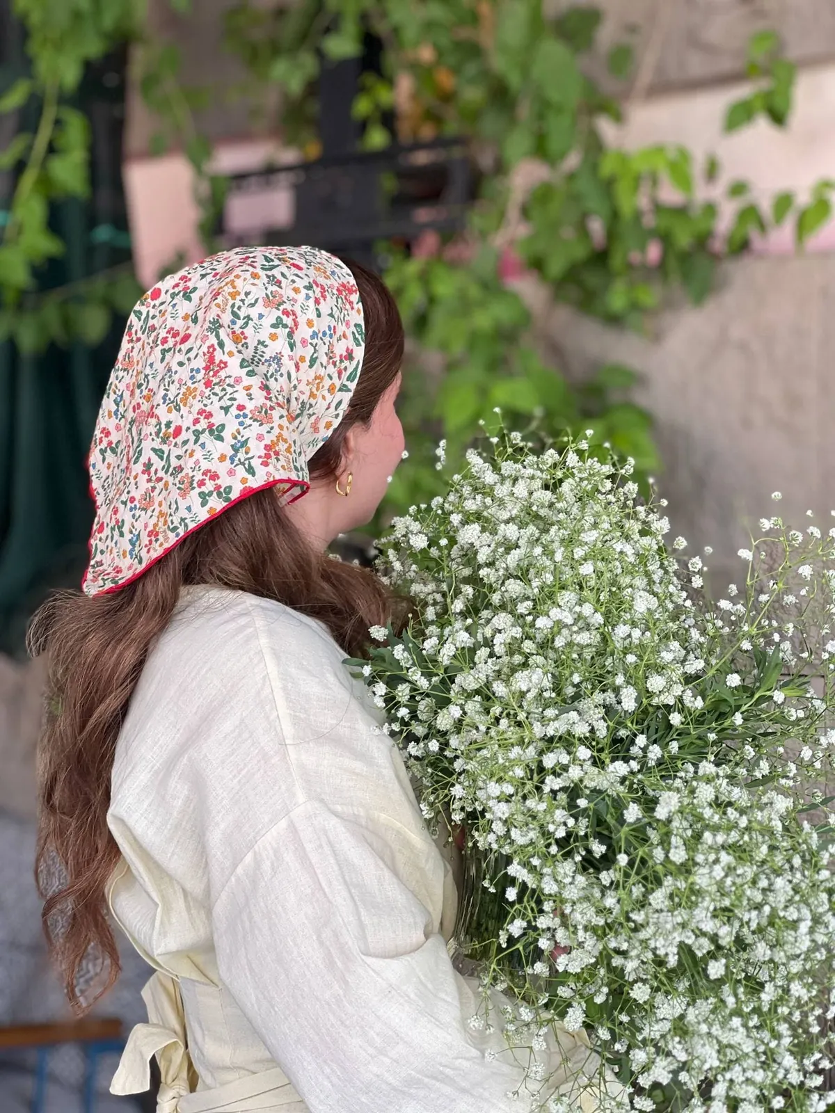 مشاركة بغطاء رأس مزهّر تحمل باقة كبيرة من زهور الجبسوفيلا