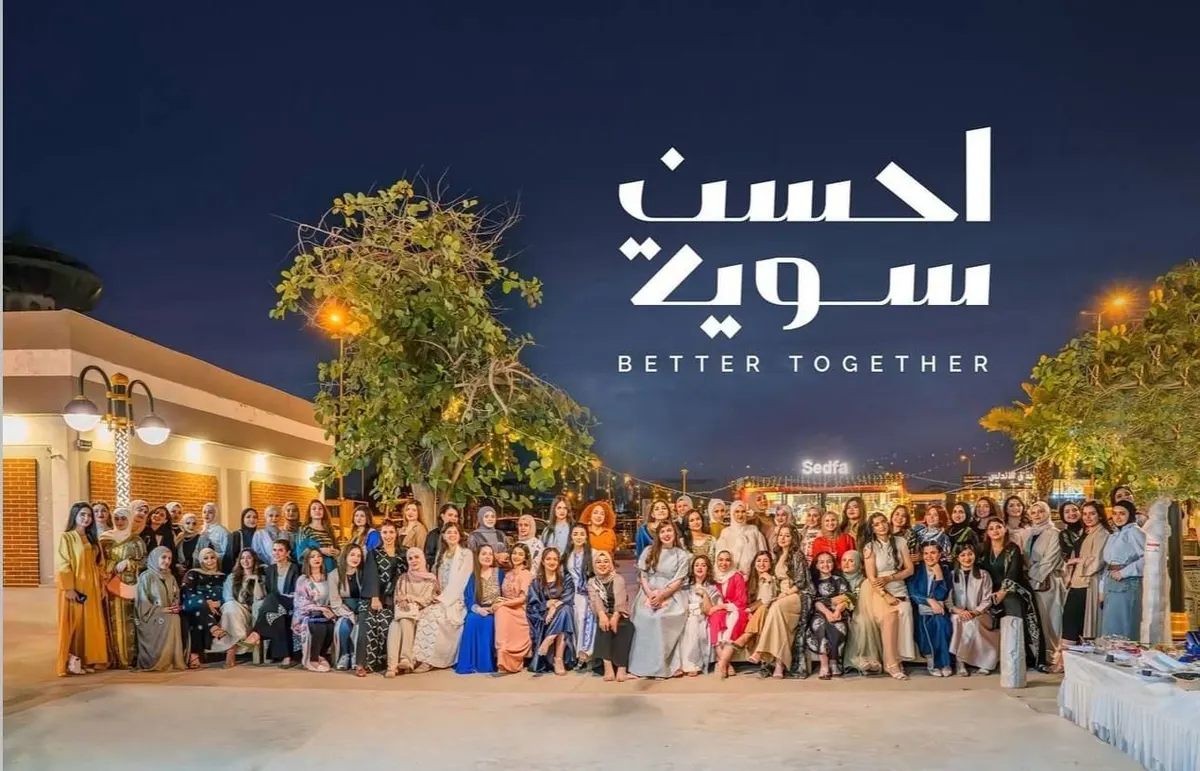 صورة جماعية ليلية لعضوات أحسن سوية في ساحة مضاءة، مع شعار أحسن سوية