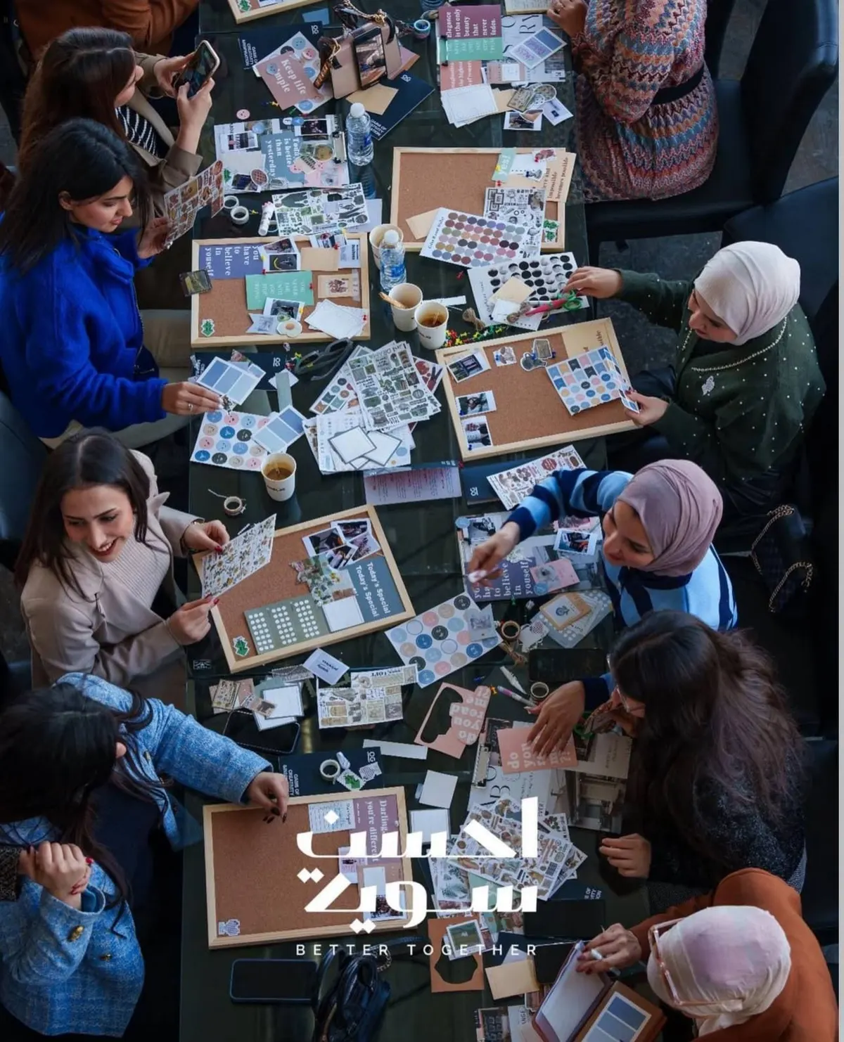 مشاركات حول طاولة يقصصن الصور ويلصقنها على ألواح الأهداف